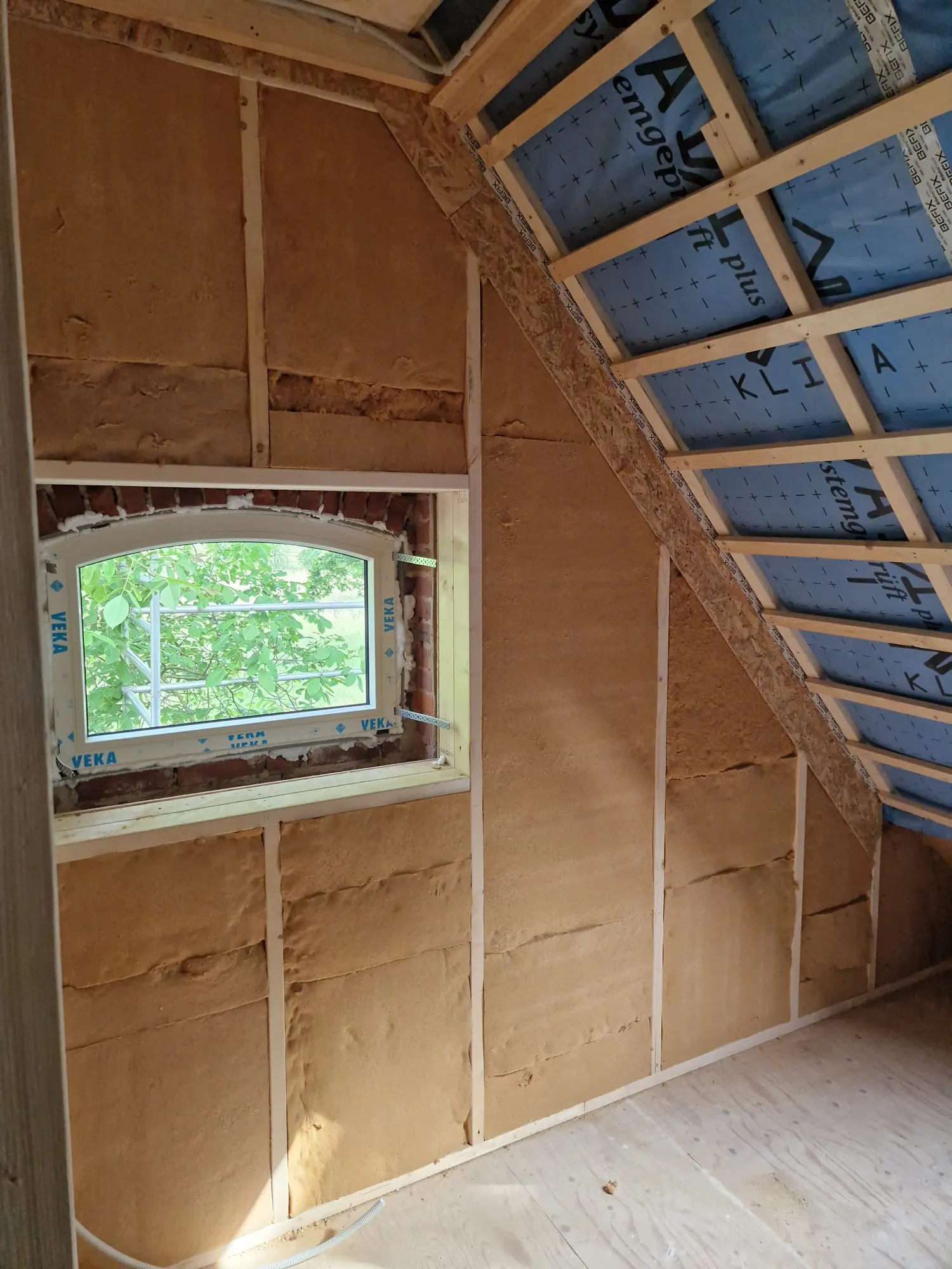 Binnenkant van een kamer onder de kap met isolatie tussen het houten regelwerk