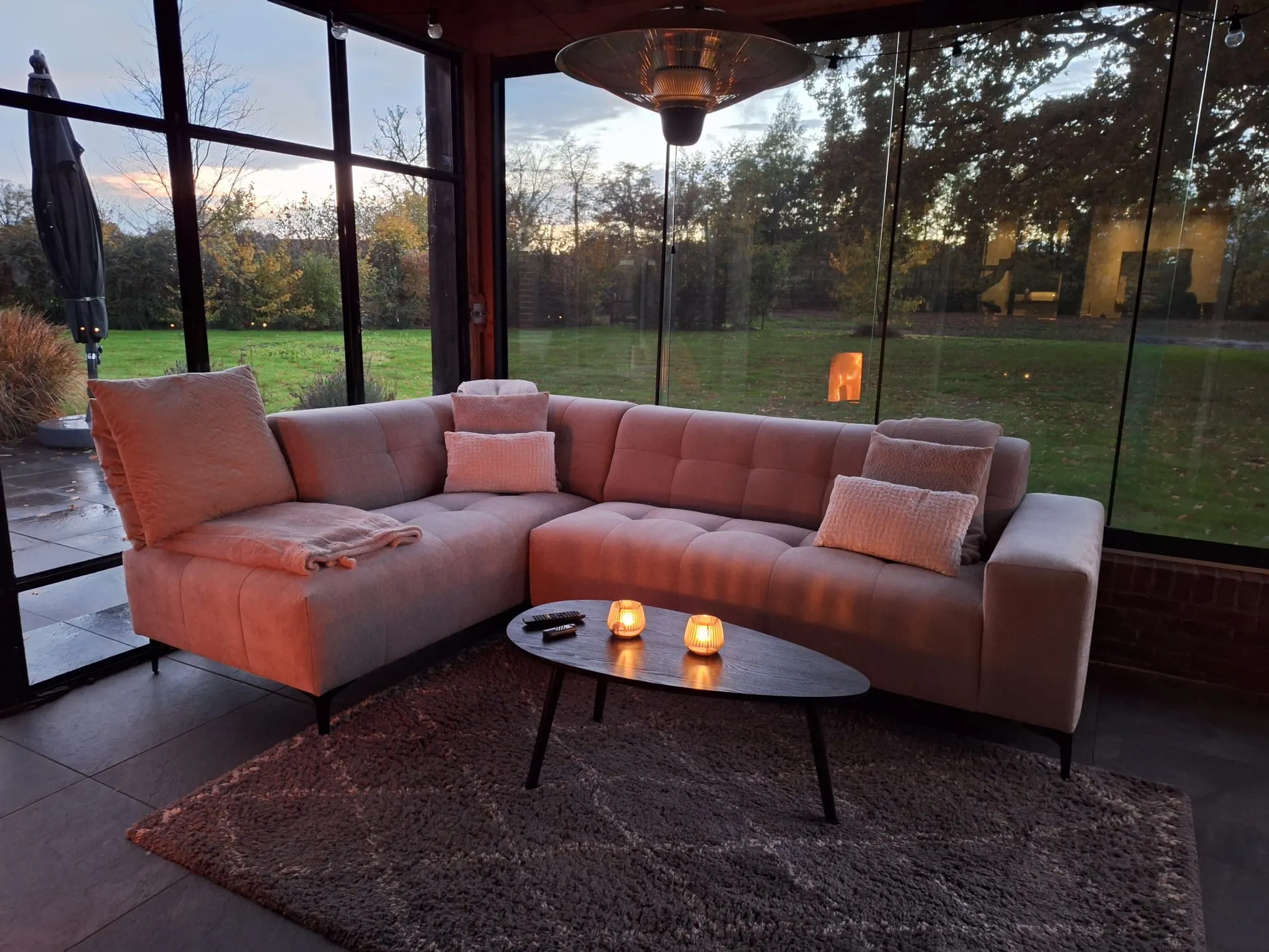 Tuinkamer met glazen wanden en zicht op een weiland in de avond